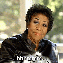 The image features Aretha Franklin sitting and giving a thoughtful expression with a slight smile. The caption reads, "hmmm..." suggesting that she is pondering something, perhaps with a hint of skepticism or amusement.